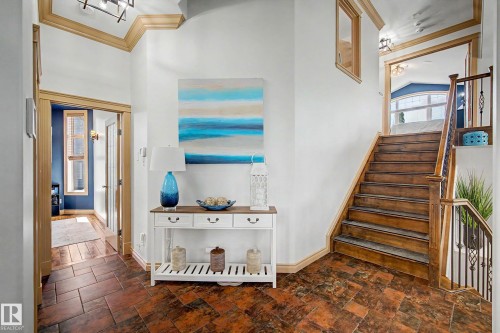 Entryway featuring wood-finish flooring, a staircase with wood treads and a wrought iron railing, and architectural trim details - 38 Longview Point(E), Spruce Grove, AB - Indoor Photo Showing Other Room