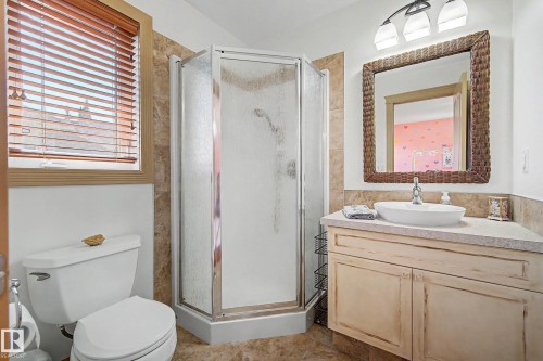 Bathroom featuring a corner shower enclosure, a single vanity with a vessel sink, a coordinating mirror, and wood-toned window blinds - 38 Longview Point(E), Spruce Grove, AB - Indoor Photo Showing Bathroom