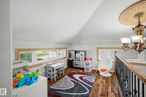 Upper-level area featuring wood-finish flooring and a decorative chandelier with a ceiling medallion - 38 Longview Point(E), Spruce Grove, AB - Indoor Photo Showing Other Room
