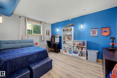 Bedroom featuring light wood-finish flooring, a window with natural light, and a blue accent wall - 38 Longview Point(E), Spruce Grove, AB - Indoor Photo Showing Bedroom