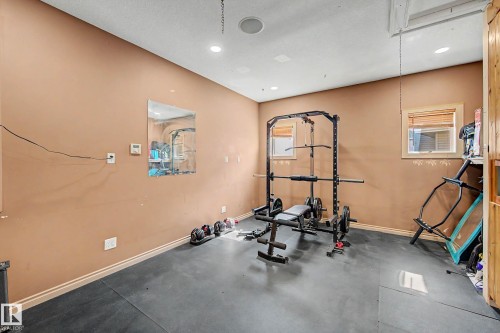 Versatile interior space featuring durable rubber flooring, two windows with wood blinds, and recessed lighting - 38 Longview Point(E), Spruce Grove, AB - Indoor Photo Showing Gym Room