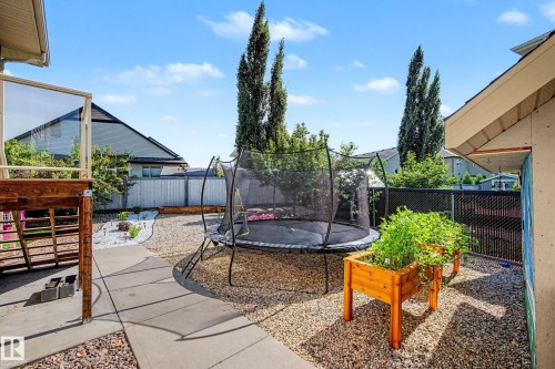 Backyard featuring a concrete patio, gravel landscaping, a raised wooden planter, and a privacy fence - 38 Longview Point(E), Spruce Grove, AB - Outdoor With Exterior