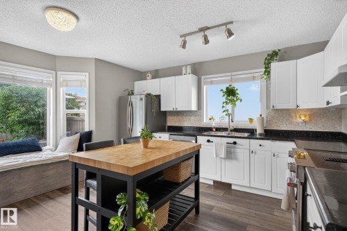 Kitchen featuring white cabinetry, dark countertops, and a butcher block island - 833 Mcallister Crescent Sw, Edmonton, AB - Indoor Photo Showing Kitchen