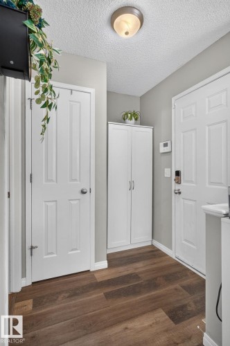 Wood-finish flooring throughout, complemented by white baseboards and trim - 833 Mcallister Crescent Sw, Edmonton, AB - Indoor Photo Showing Other Room