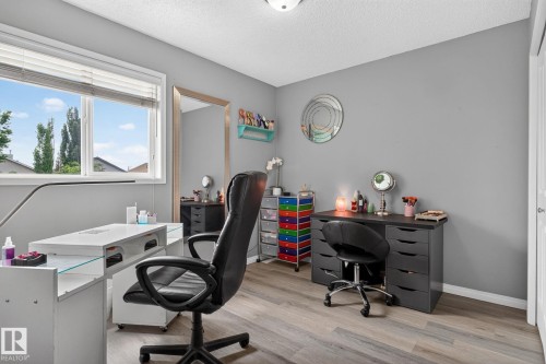 Spacious room featuring wood-finish flooring, a large window with blinds, and light gray painted walls - 833 Mcallister Crescent Sw, Edmonton, AB - Indoor Photo Showing Office