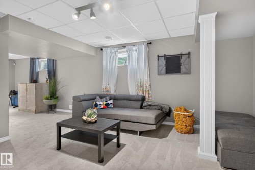 Finished lower level featuring light gray carpeting, recessed lighting, drop ceiling, and a structural column with decorative trim - 833 Mcallister Crescent Sw, Edmonton, AB - Indoor