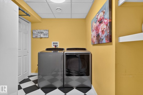 Utility area featuring a checkered floor, warm yellow walls, a white paneled door, and a drop ceiling with recessed lighting - 833 Mcallister Crescent Sw, Edmonton, AB - Indoor Photo Showing Laundry Room