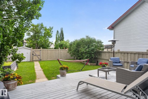 Expansive backyard featuring a gray wood-finish deck, a manicured lawn, and mature perimeter trees - 833 Mcallister Crescent Sw, Edmonton, AB - Outdoor With Deck Patio Veranda