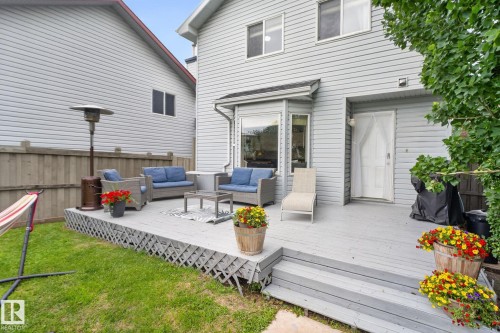 Rear exterior featuring a spacious wood deck, white vinyl siding, and a fenced yard with mature trees - 833 Mcallister Crescent Sw, Edmonton, AB - Outdoor With Deck Patio Veranda With Exterior