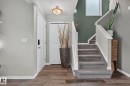 Foyer with wood-finish flooring, two-tone wall paint, and a carpeted staircase with white railings - 833 Mcallister Crescent Sw, Edmonton, AB  - Indoor Photo Showing Other Room 