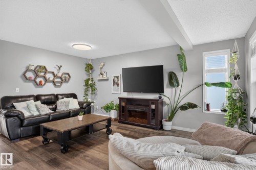 Spacious living area featuring wood-finish flooring, light gray walls, and a recessed ceiling beam - 833 Mcallister Crescent Sw, Edmonton, AB - Indoor Photo Showing Living Room
