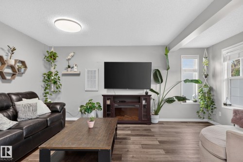 Spacious living area featuring wood-finish flooring, light gray wall paint, and multiple windows - 833 Mcallister Crescent Sw, Edmonton, AB - Indoor Photo Showing Living Room