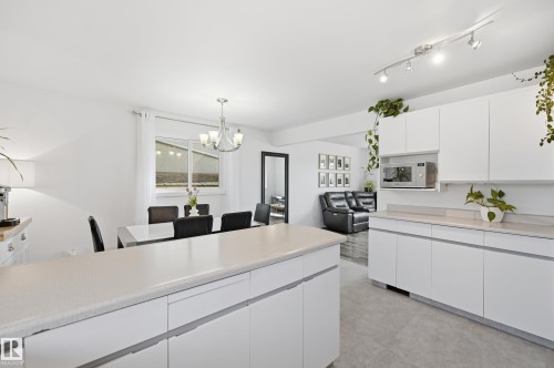 Modern kitchen featuring white cabinetry, light-toned countertops, and track lighting - 15111 67 Street Nw, Edmonton, AB - Indoor Photo Showing Kitchen