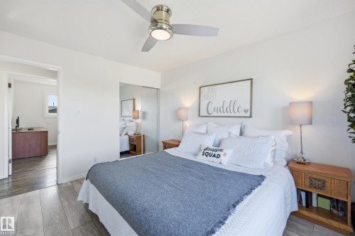 Bedroom featuring wood-finish flooring, a contemporary ceiling fan, and built-in mirrored closet doors - 15111 67 Street Nw, Edmonton, AB - Indoor Photo Showing Bedroom