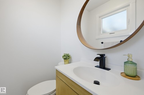 Bathroom featuring a wood-finish vanity with an integrated sink, white countertop, and a matte black waterfall faucet - 15111 67 Street Nw, Edmonton, AB - Indoor Photo Showing Bathroom