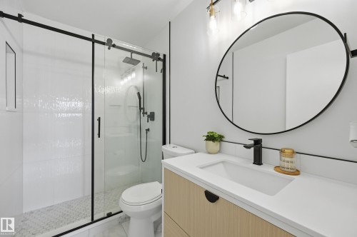 Modern bathroom featuring a glass-enclosed shower with matte black fixtures, white textured subway tile, and a hexagonal mosaic shower floor - 15111 67 Street Nw, Edmonton, AB - Indoor Photo Showing Bathroom