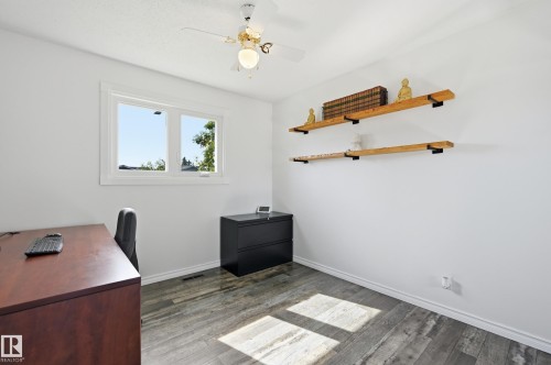 Bright room featuring wood-finish flooring, a white trim window, built-in shelving, and a ceiling fan with integrated lighting - 15111 67 Street Nw, Edmonton, AB - Indoor