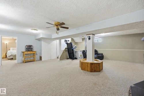 Expansive carpeted room featuring a ceiling fan, recessed lighting, and a wood-paneled column with integrated lighting - 15111 67 Street Nw, Edmonton, AB - Indoor