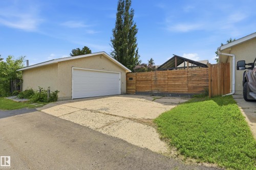 Detached garage with a white overhead door, concrete driveway, and a horizontal wood privacy fence - 15111 67 Street Nw, Edmonton, AB - Outdoor With Exterior
