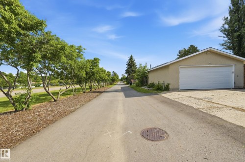 Detached garage with a white garage door, tan stucco exterior, and a peaked roofline - 15111 67 Street Nw, Edmonton, AB - Outdoor