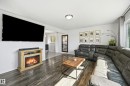 Living area featuring wood-finish flooring, a decorative fireplace, and a large window with natural light - 15111 67 Street Nw, Edmonton, AB  - Indoor Photo Showing Living Room With Fireplace 