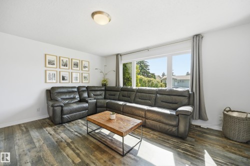 Spacious living area featuring wood-finish flooring, white walls, and a large window with exterior views - 15111 67 Street Nw, Edmonton, AB - Indoor Photo Showing Living Room