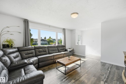 Spacious interior featuring large windows, wood-finish flooring, and white painted walls - 15111 67 Street Nw, Edmonton, AB - Indoor Photo Showing Living Room