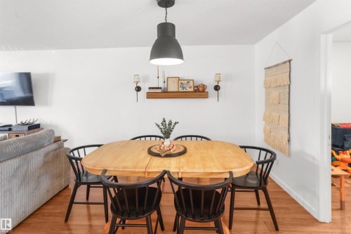 Dining area featuring wood-finish flooring, white walls, and a recessed wall shelf with sconce lighting - 679 Kananaskis Drive, Devon, AB - Indoor Photo Showing Dining Room