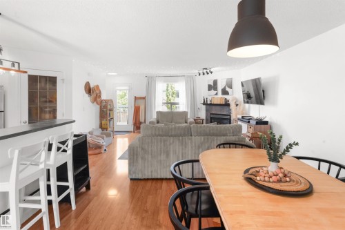 Open-concept living space featuring wood-finish flooring, a built-in fireplace, and a kitchen counter with seating - 679 Kananaskis Drive, Devon, AB - Indoor With Fireplace