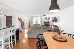 Open-concept living space featuring wood-finish flooring, a built-in fireplace, and a kitchen counter with seating - 
