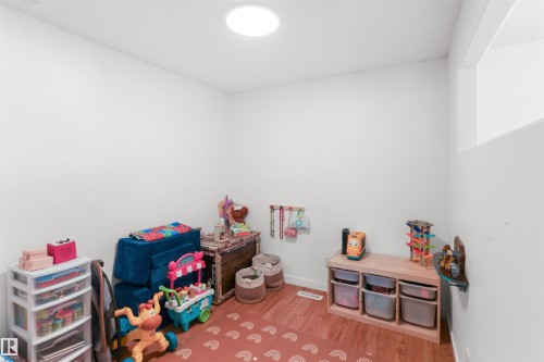 Recessed ceiling light with a high-set window and wood-finish flooring - 679 Kananaskis Drive, Devon, AB - Indoor Photo Showing Other Room