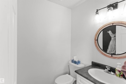 Bathroom vanity with a white basin sink, dark countertop, and chrome faucet - 679 Kananaskis Drive, Devon, AB - Indoor Photo Showing Bathroom