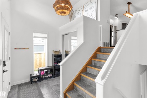 Entryway featuring high ceilings, a decorative woven pendant light fixture, and a staircase with wood-finish treads and tile risers - 679 Kananaskis Drive, Devon, AB - Indoor Photo Showing Other Room