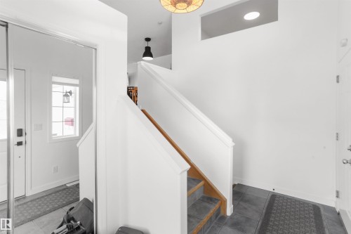 Entryway featuring a white staircase with wood-finish handrail, dark gray tile flooring, and a semi-flush mount ceiling light fixture - 679 Kananaskis Drive, Devon, AB - Indoor Photo Showing Other Room