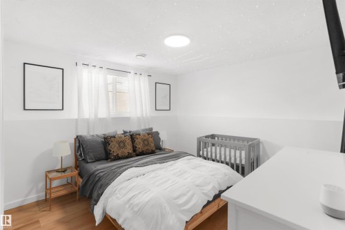 Room featuring wood-finish flooring, a window with blinds and sheer curtains, and a ceiling light fixture - 679 Kananaskis Drive, Devon, AB - Indoor Photo Showing Bedroom
