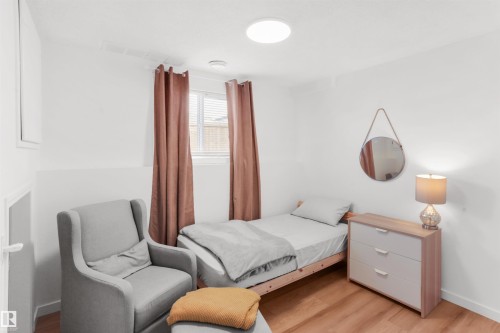 Bright room featuring wood-finish flooring, a flush-mount ceiling light, and a window with blinds and drapes - 679 Kananaskis Drive, Devon, AB - Indoor Photo Showing Bedroom