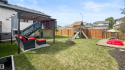 Expansive backyard featuring a manicured lawn, full privacy fencing, and a built-in fire pit - 