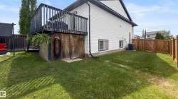 Spacious backyard with a wooden deck, white vinyl siding, and a privacy fence - 