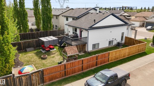 Expansive backyard featuring a manicured lawn, full perimeter fencing, and a multi-level deck with black railing - 679 Kananaskis Drive, Devon, AB - Outdoor With Exterior