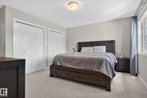 Bedroom featuring two sets of bi-fold closet doors, neutral wall paint, and carpet flooring - 319 Desrochers Boulevard Sw, Edmonton, AB - Indoor Photo Showing Bedroom