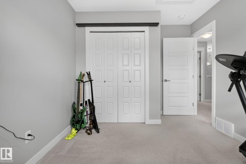 Neutral-toned room featuring a closet with bi-fold paneled doors, light grey wall paint, white trim, and light-colored carpeting - 319 Desrochers Boulevard Sw, Edmonton, AB - Indoor