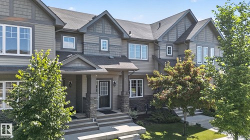 Townhome exterior featuring horizontal siding, stone accents, multiple gable roofs, white-framed windows, and covered entryways - 319 Desrochers Boulevard Sw, Edmonton, AB - Outdoor With Facade