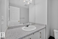Vanity featuring a speckled countertop, integrated sink, and white cabinetry with brushed nickel hardware - 