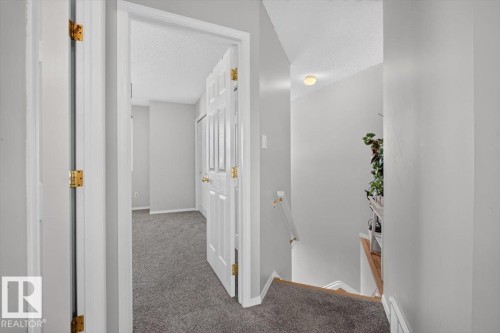 Hallway featuring light gray wall paint, white trim, and dark gray carpet flooring - #18 345 Kirkness Rd Nw, Edmonton, AB - Indoor Photo Showing Other Room