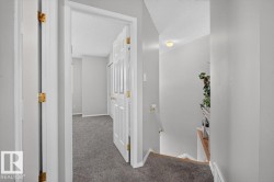 Hallway featuring light gray wall paint, white trim, and dark gray carpet flooring - 