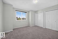 Carpeted room with a multi-pane window, two sets of bifold closet doors, light gray walls, and a ceiling-mounted light fixture - 