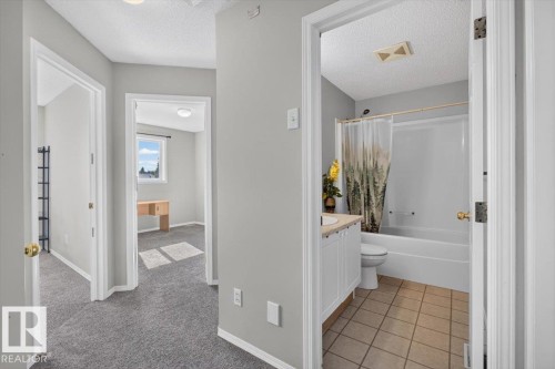 Hallway with gray carpeting, leading to multiple rooms - #18 345 Kirkness Rd Nw, Edmonton, AB - Indoor