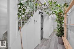 Integrated laundry station featuring stacked appliances, light wood-finish flooring, recessed lighting, and white paneled walls - 