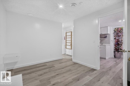 Bright interior space featuring light wood-finish flooring, recessed lighting, and a white color palette - #18 345 Kirkness Rd Nw, Edmonton, AB - Indoor Photo Showing Other Room