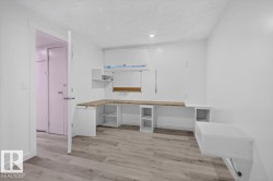 Built-in L-shaped desk with a light-toned countertop, integrated shelving, and wood-finish flooring - 